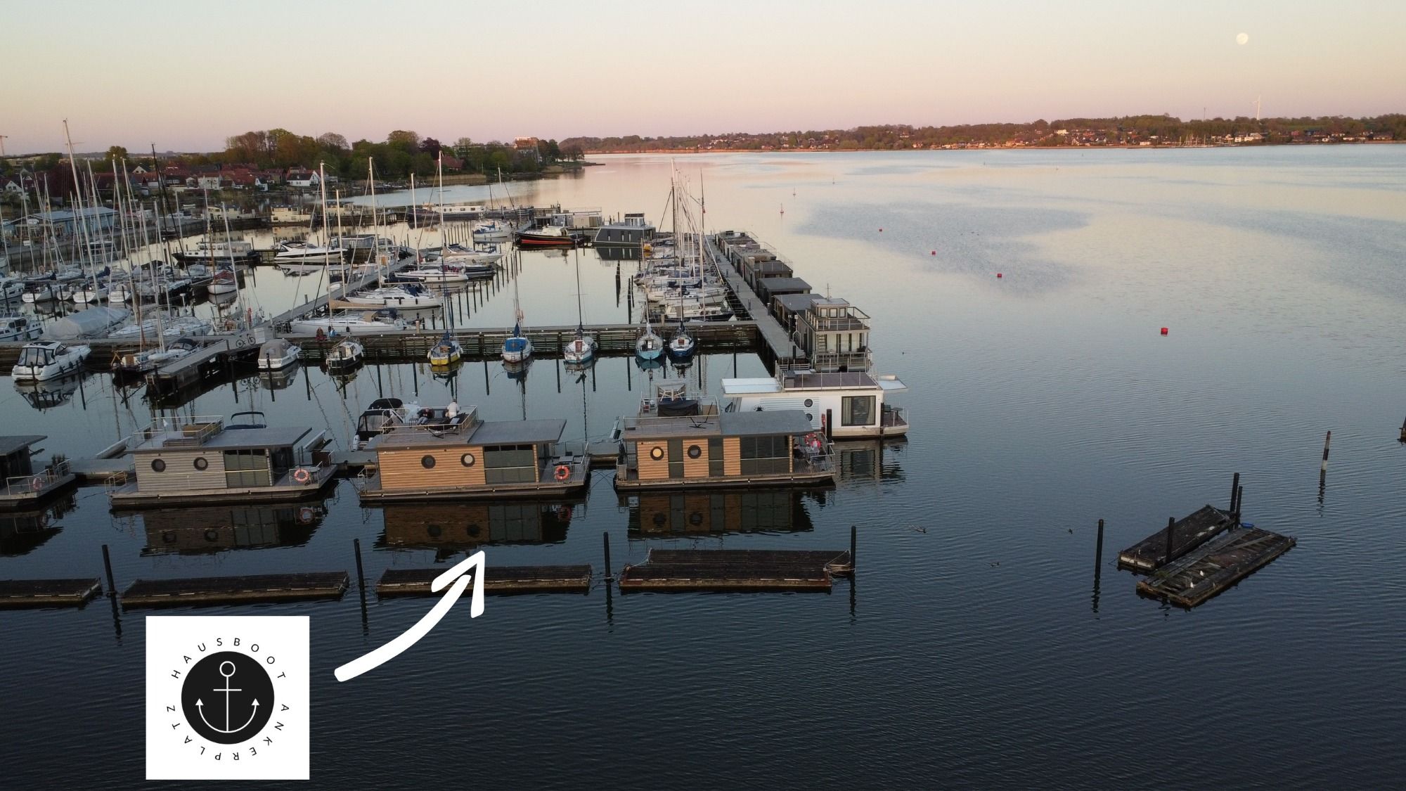 Man sieht Hausboot Ankerplatz in vorderster Reihe im Stadthafen von Schleswig liegen. Weitere Hausboote und Segelboote sind zu sehen. 